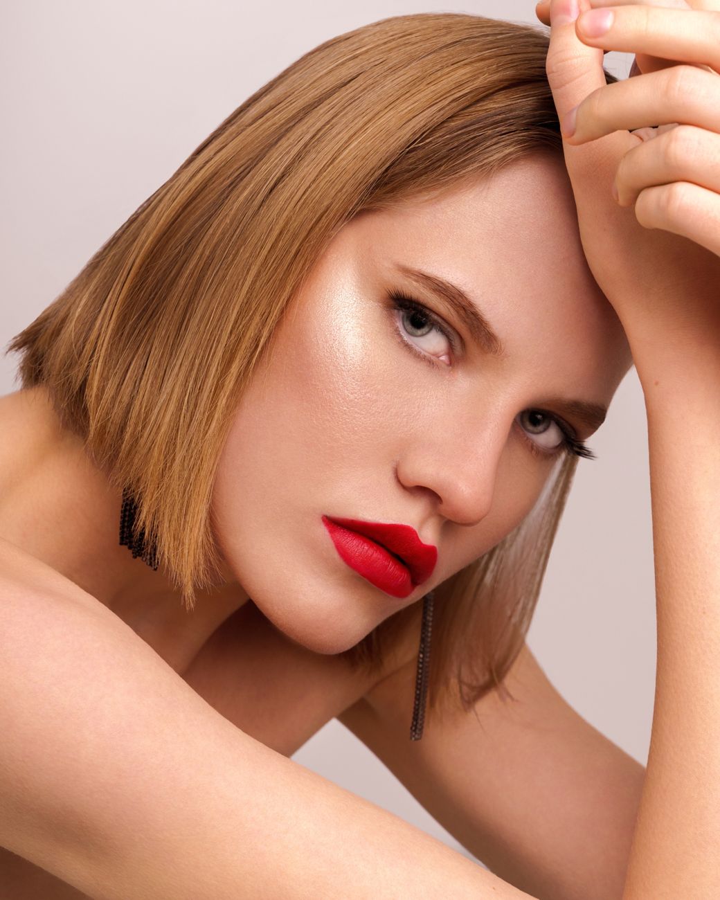 Model with a sleek bob and red lips resting her head on her arms