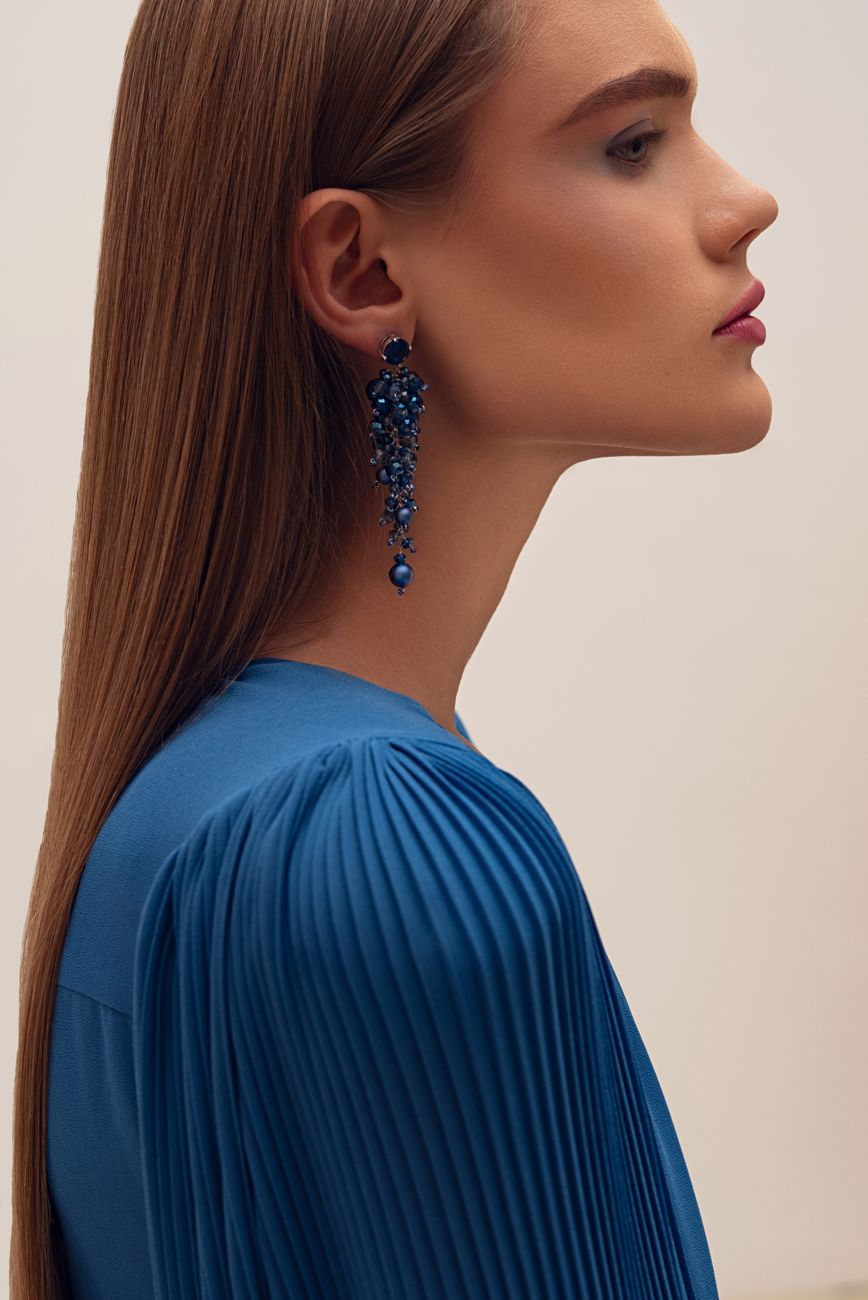 Profile of a model wearing a long blue beaded earring