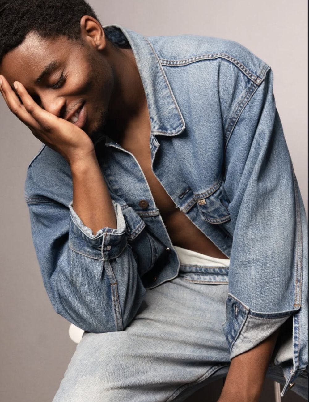 Man in an oversized denim jacket laughing