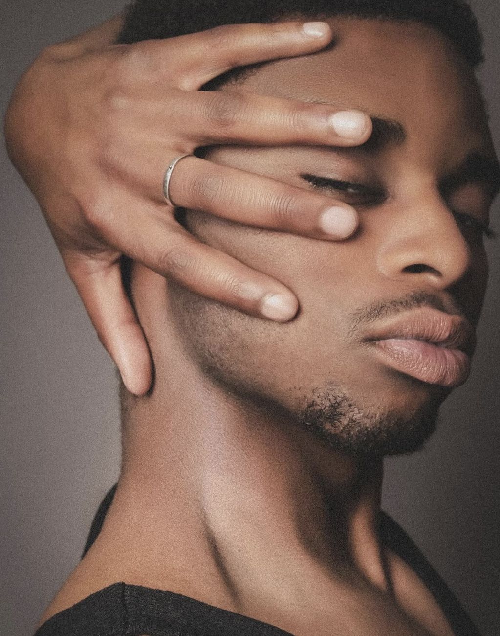 Man with his hand across his face, wearing a silver ring
